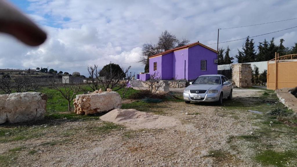 ein Auto, das vor einem lila Haus parkt in der Unterkunft Jerash mountain studio chalet شاليه جبال جرش و عجلون in Gerasa