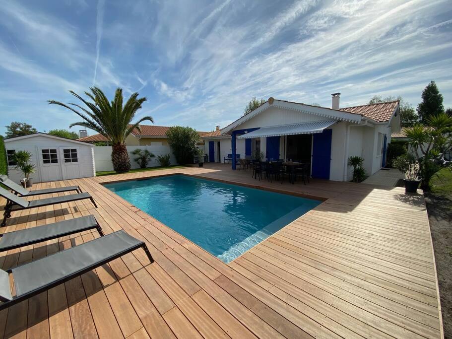 a swimming pool with a wooden deck and a house at Maison moderne avec piscine in La Teste-de-Buch