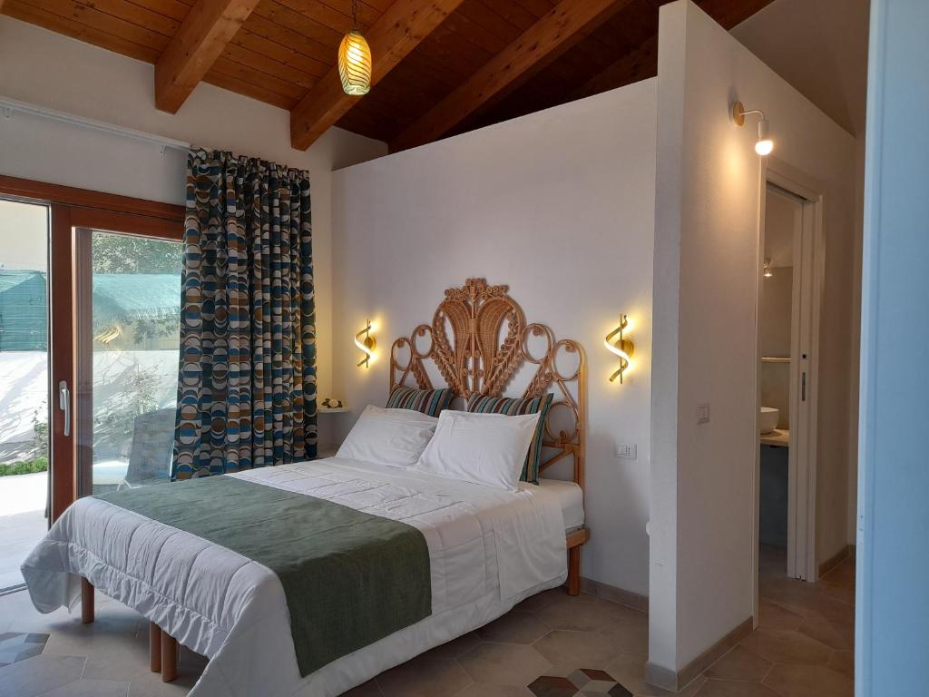 una camera con un grande letto con testiera in legno di Girasole Boutique B&B a Riola Sardo