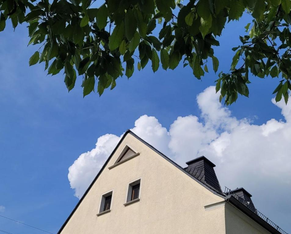 uma casa contra um céu azul com nuvens em FeWo Weitblick in Höhenlage von Greiz em Greiz