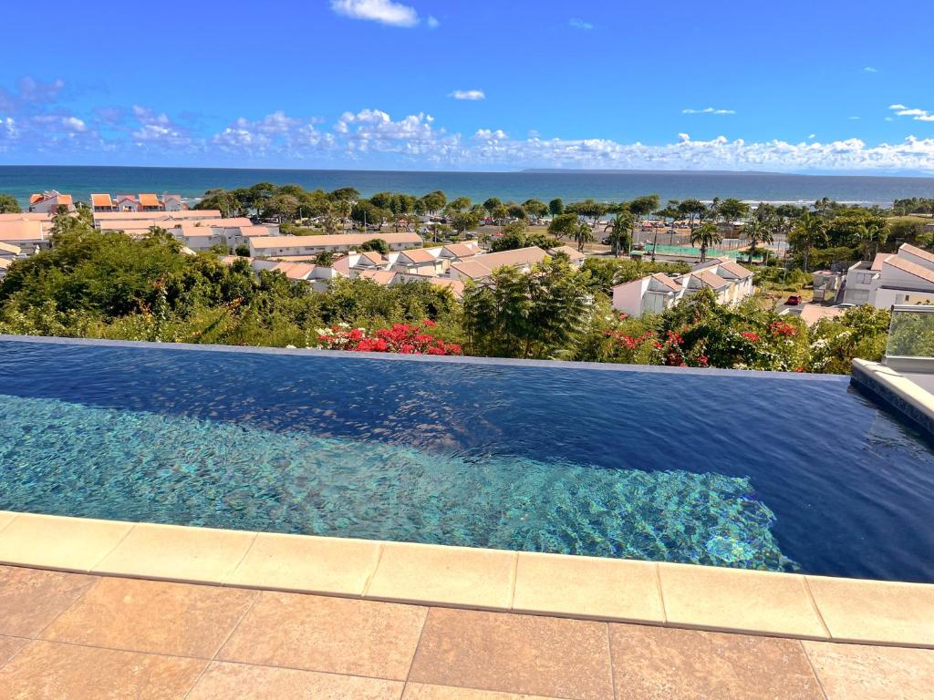 a swimming pool with a view of the ocean at Résidence Les Raisins Clairs - Villas standing 4 étoiles , vue sur mer panoramique & piscine à débordement in Saint-François