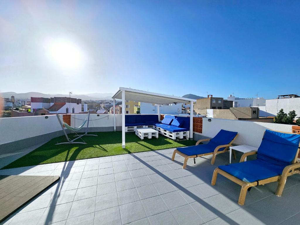 einen Balkon mit blauen Stühlen und einem Tisch auf dem Dach in der Unterkunft St George's Apartments - Gran Canaria in Telde