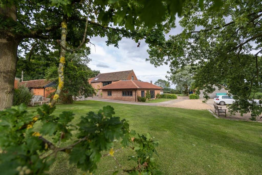 a house with a car parked in front of a yard at The Granary - Wood Farm Barn. Luxury Barn with wonderful countryside views in Bawdeswell