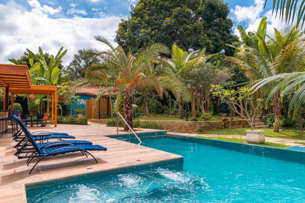 una piscina con 2 sillas y una terraza de madera en Pouso, Café e Cultura en Pirenópolis