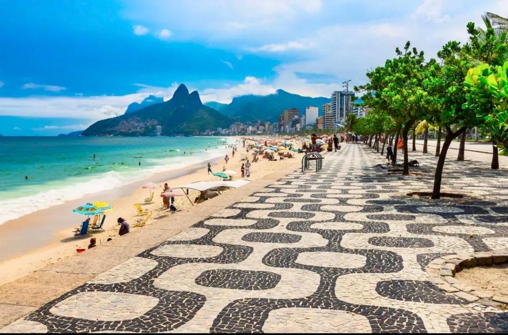 - une plage avec des personnes assises sur le sable et l'océan dans l'établissement Apartamento Studio Deluxe HIR 37, à Rio de Janeiro