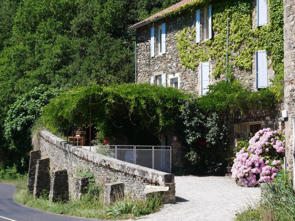 un edificio in pietra con una recinzione e fiori di fronte ad esso di Les Jardins de Lumière a Brusque