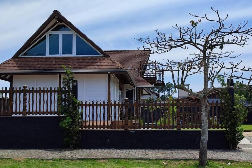 uma casa com uma cerca de madeira e uma árvore em Deslumbrante Casa Frente Lagoa em Balneario Barra do Sul