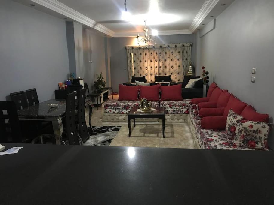 a living room with a red couch and a table at Lovely 3-bedroom rental unit.cozy and friendly in Cairo