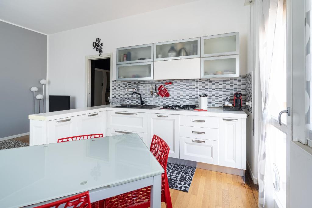 eine weiße Küche mit weißen Schränken und roten Stühlen in der Unterkunft appartamento luce del lago in Salò