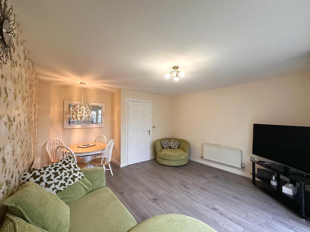 a living room with a couch and a table and a tv at 4 Bed Town House with free parking in Eaton Socon