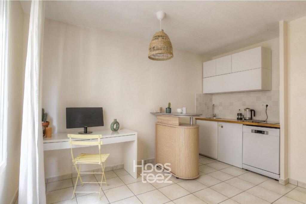 a kitchen with white cabinets and a table and a chair at Le calme et cosy avec parking gratuit in Lyon
