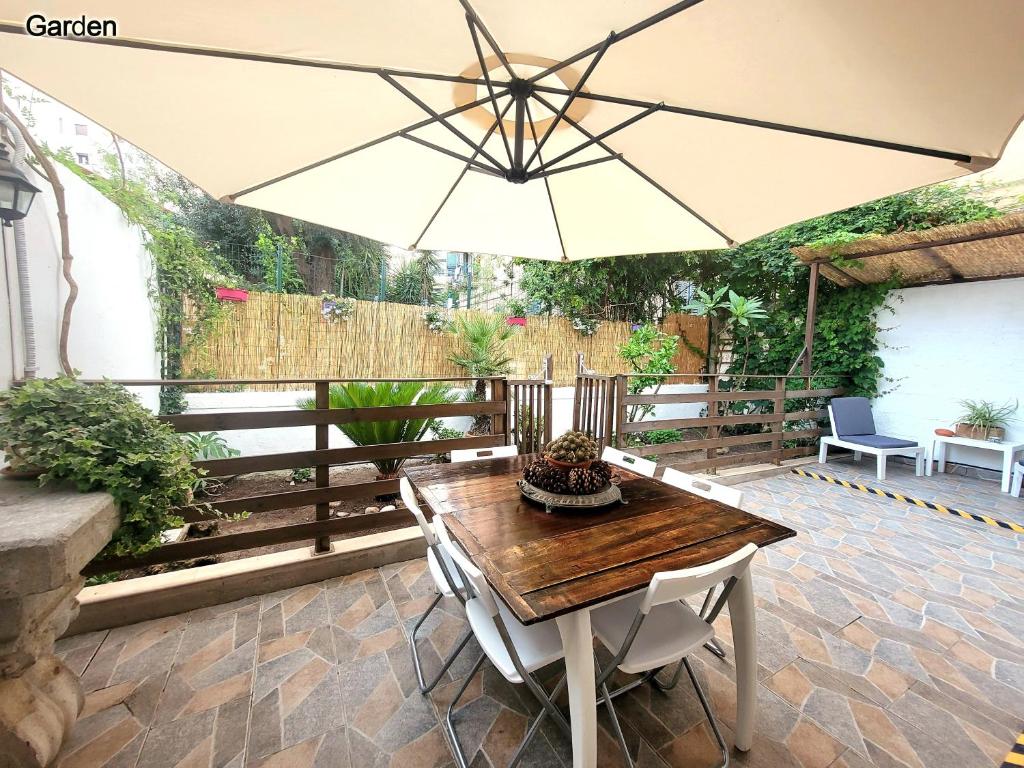 a patio with a wooden table and an umbrella at Leoni63 in Palermo