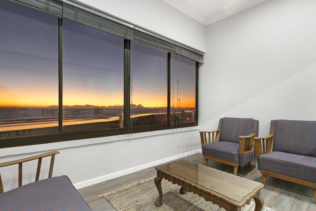 un salon avec deux chaises et une table et de grandes fenêtres dans l'établissement Jacquelena Hof 9, à Strand