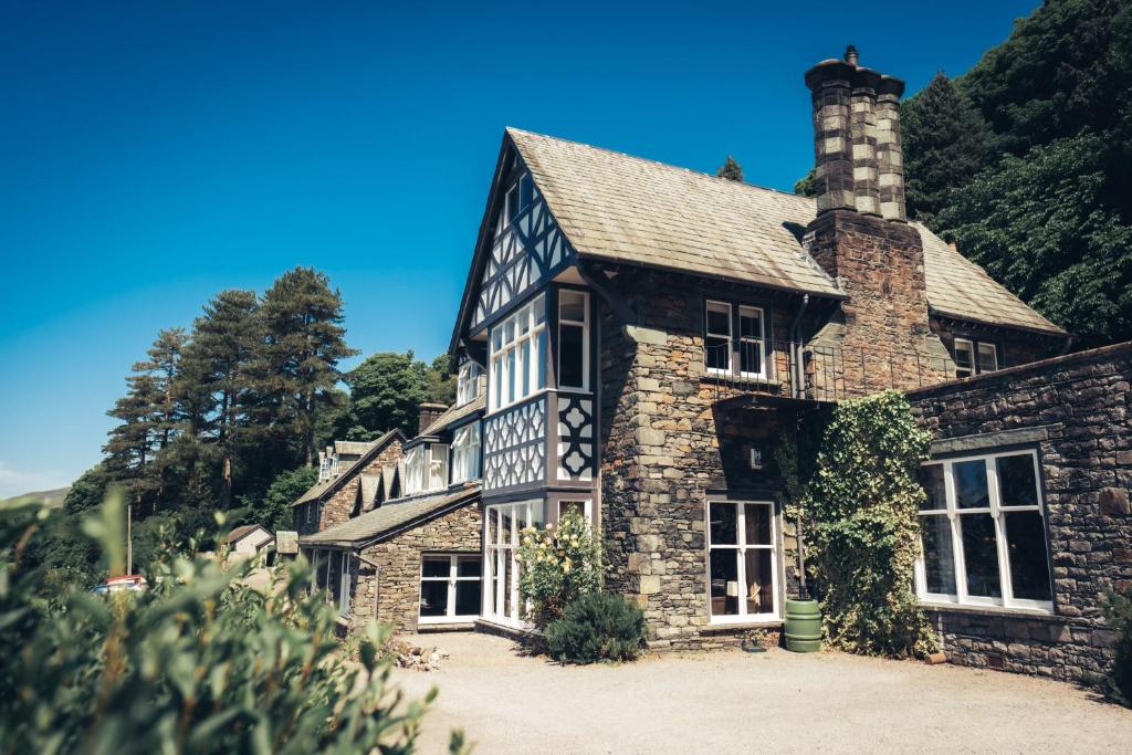 una vecchia casa in pietra con un camino su una collina di Ravenstone Manor a Keswick