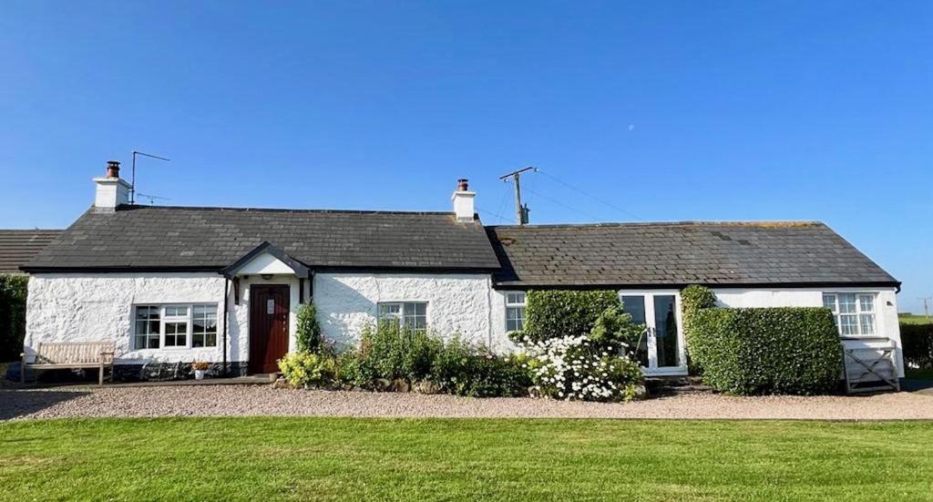 uma casa branca com um telhado preto em Tornaroan Cottage em Ballycastle