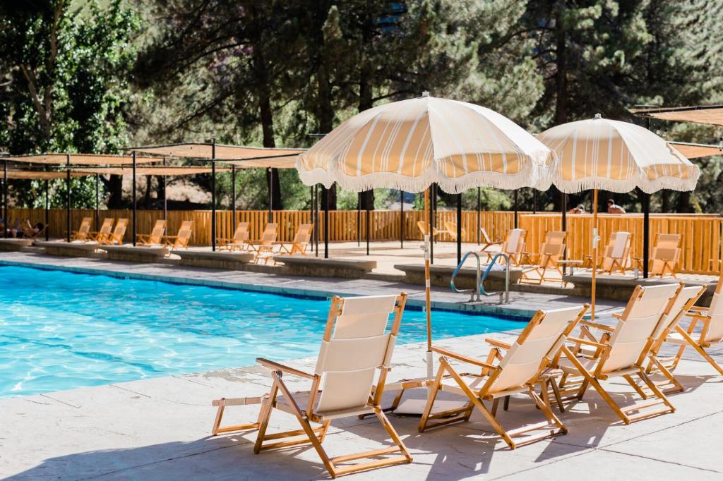 a group of chairs and umbrellas next to a swimming pool at Huttopia Paradise Springs in Valyermo