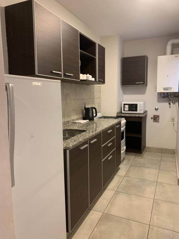 a kitchen with black cabinets and a white refrigerator at Hermoso y calido depto centrico in Villa Carlos Paz