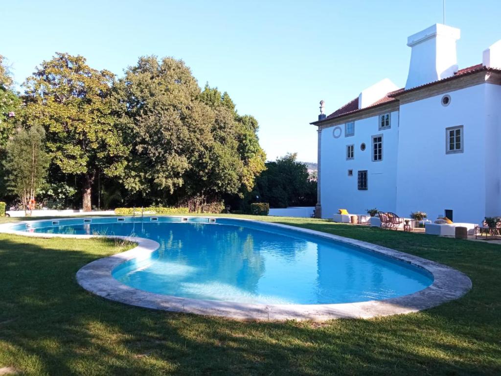 een zwembad in een tuin naast een gebouw bij Palácio da Portela III in Coimbra