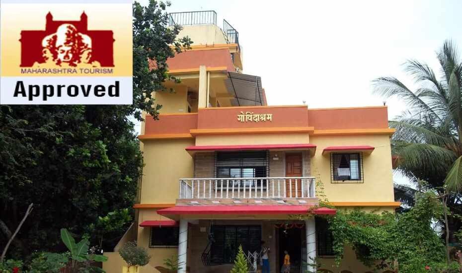 a yellow and red building with a balcony at Govindaashram in Bhogwe