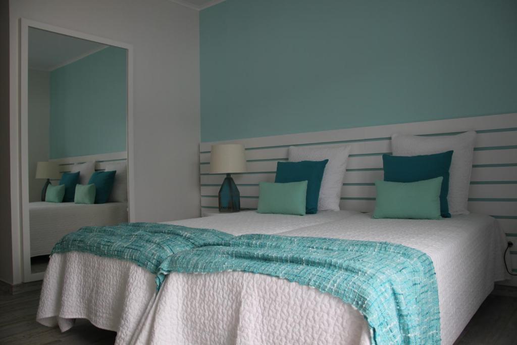 a bedroom with a large bed with blue and green pillows at Vila Mar in Vila Franca do Campo