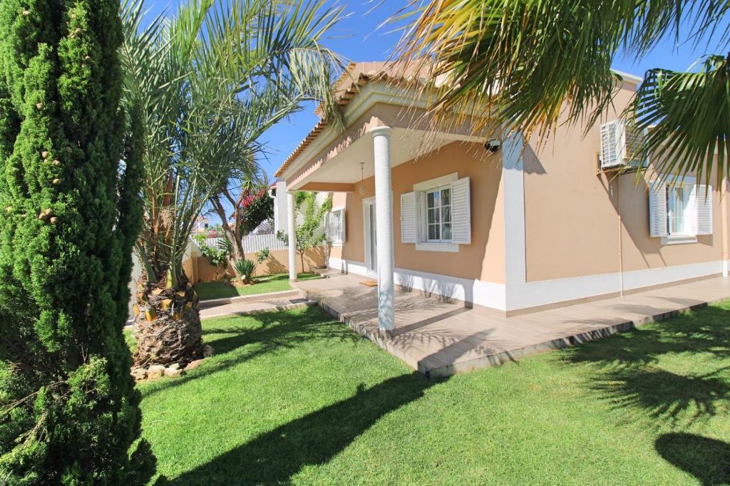 ein Haus mit einer Palme im Hof in der Unterkunft Villa Ribeiro By Keys to Algarve in Armação de Pêra