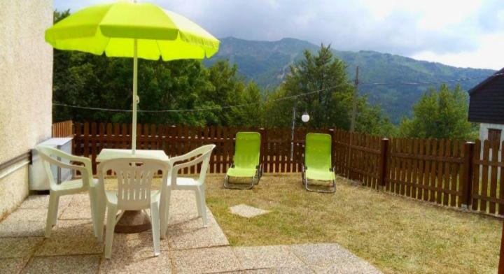 eine Terrasse mit einem Tisch, Stühlen und einem Sonnenschirm in der Unterkunft Monolocale Il Capriolo - Abetone in Abetone