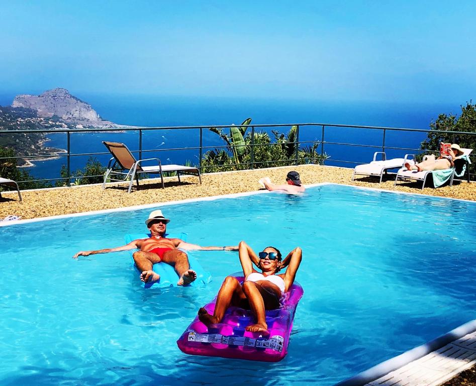 un grupo de personas sentadas en una piscina en cefalù nest pool house terrace sea view, en Cefalú