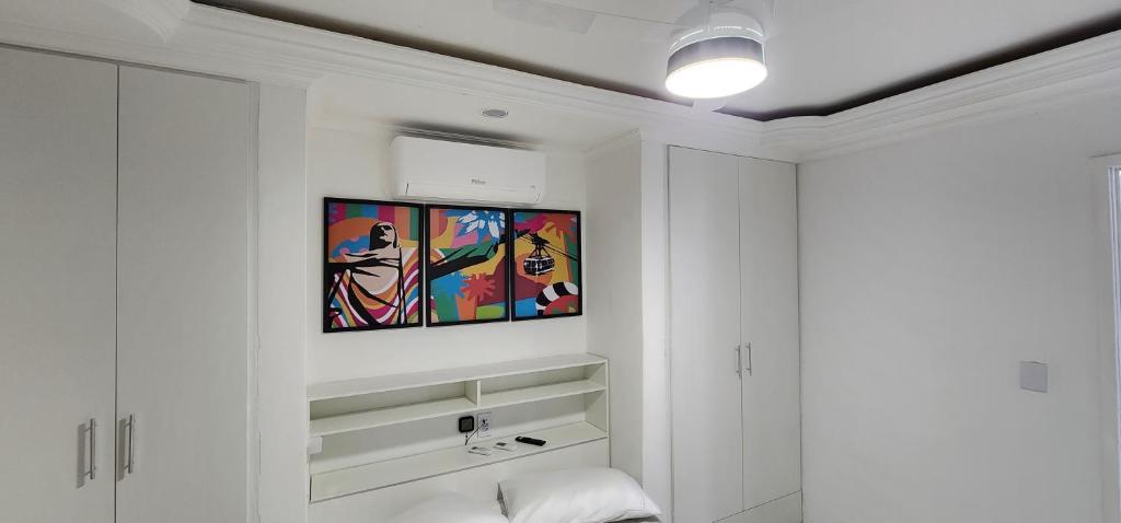 une chambre blanche avec un tableau sur le mur dans l'établissement Apart Hotel Farol de Itapuã - Duas suítes com cozinha completa à 250m da praia e farol de Itapuã, à Salvador