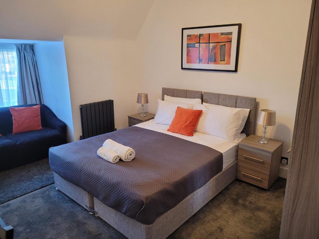a bedroom with a large bed and a blue chair at Silvertree Lodge - 2 double bed flat with parking in Hemel Hempstead