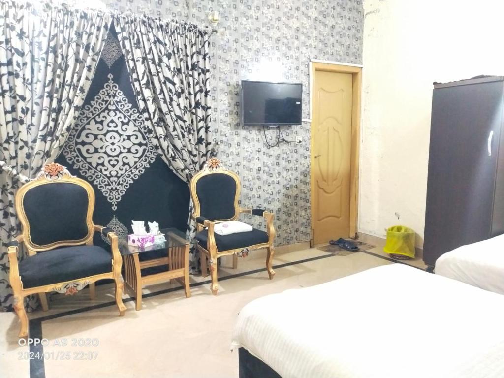 拉合爾的住宿－Hotel Eden Plus Lahore，一间卧室配有两把椅子和一台墙上的电视