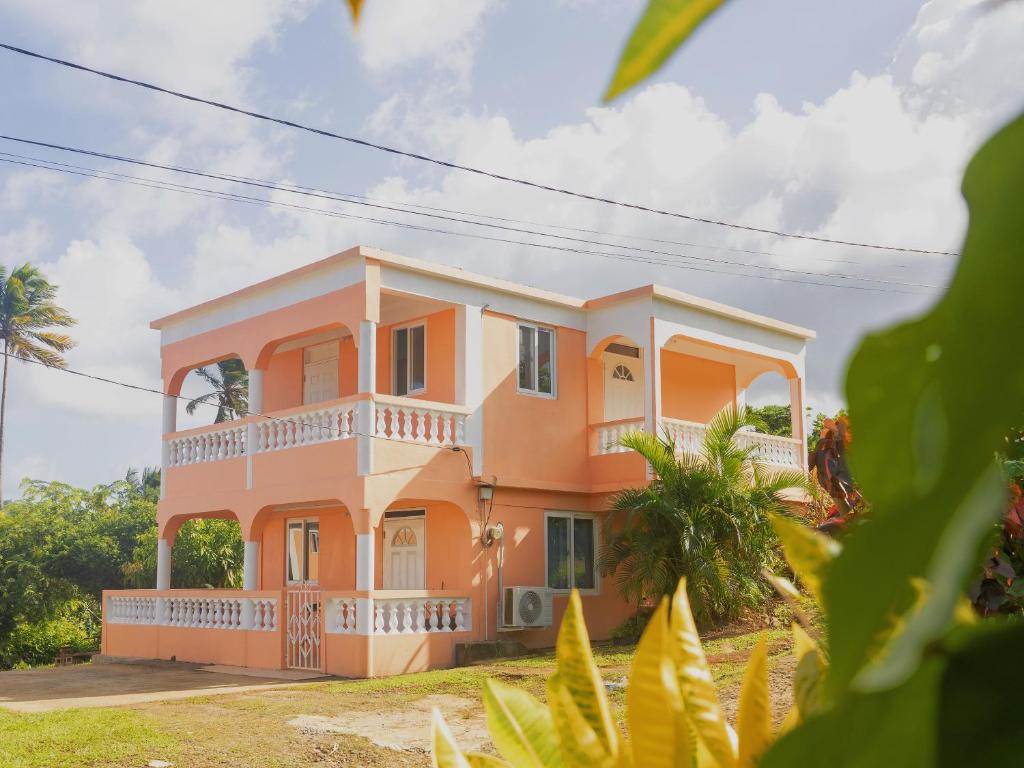 a peach colored house with a balcony at Happy Nest Dominica in Marigot