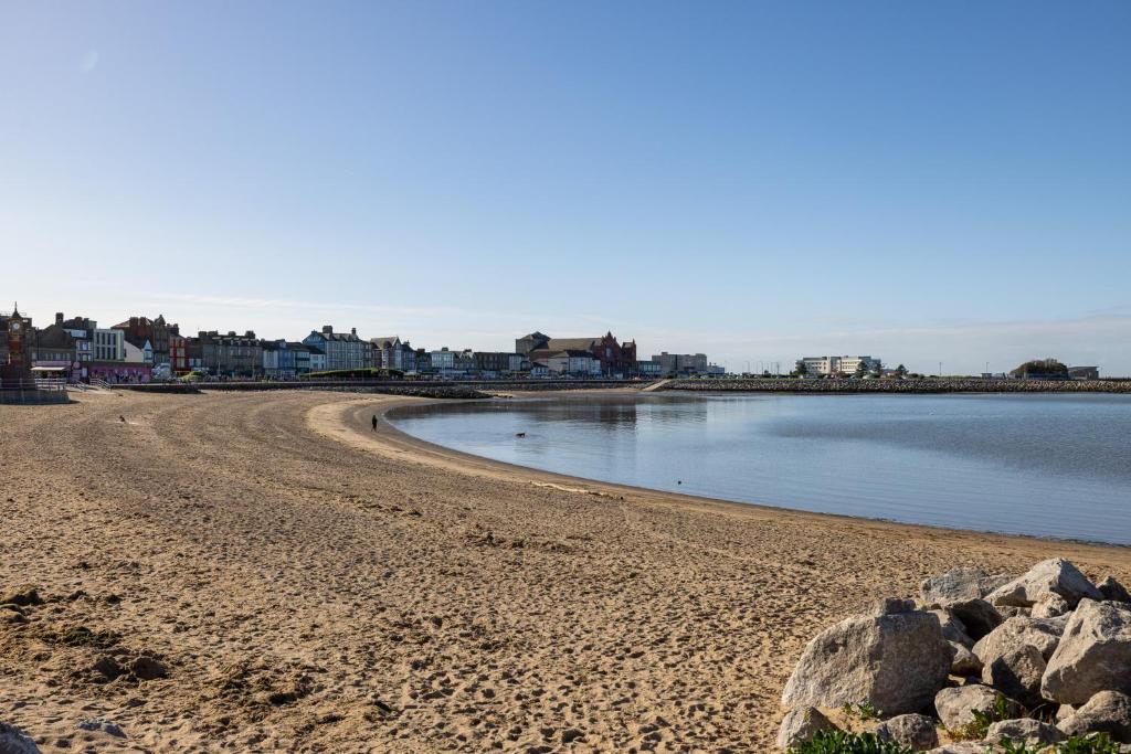 a sandy beach with rocks and a body of water at Eden Rose Cottage in Morecambe