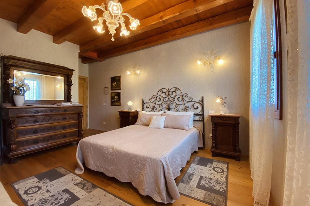 - une chambre avec un lit et un lustre dans l'établissement Al Vecchio Fienile, à San Michele al Tagliamento