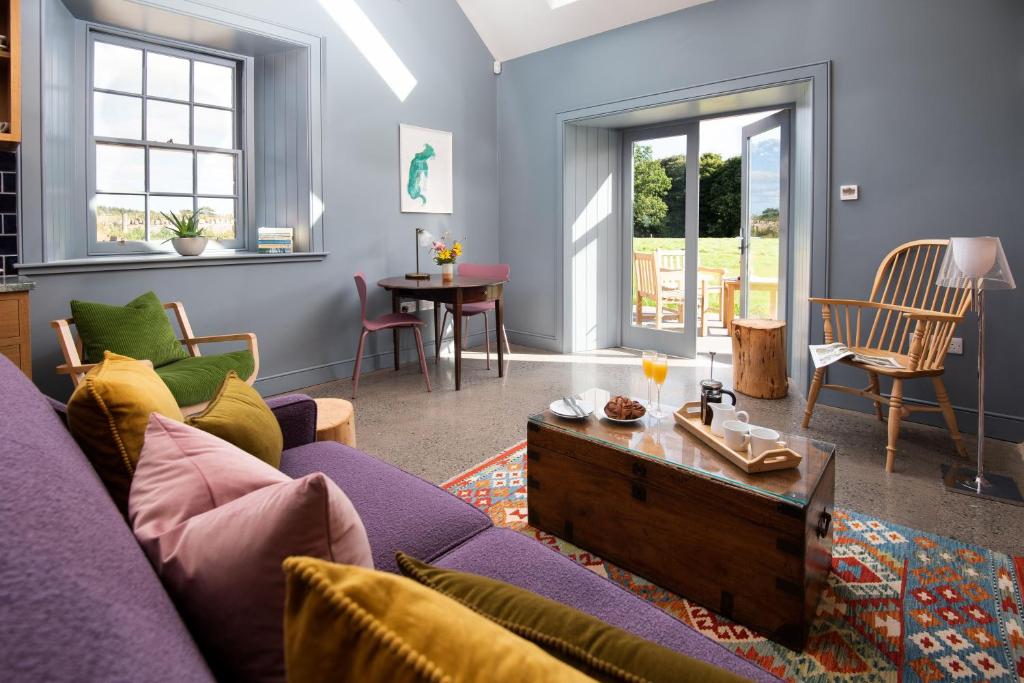 a living room with a purple couch and a table at Ploughman's Bothy at Papple Steading in East Linton