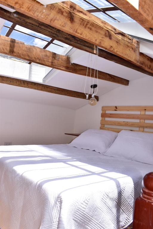 a bedroom with a bed with white sheets and wooden ceilings at Apartaestudio Loft 202 - UE Home in Duitama