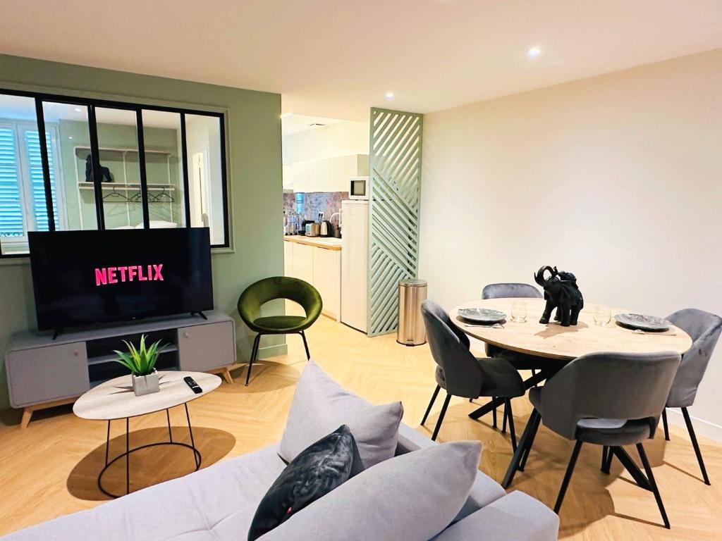 ein Wohnzimmer mit einem Sofa und einem Tisch mit einem TV in der Unterkunft Le Scandinave - PROCHE MACON - PARKING GRATUIT - NETFLIX in Pont-de-Veyle