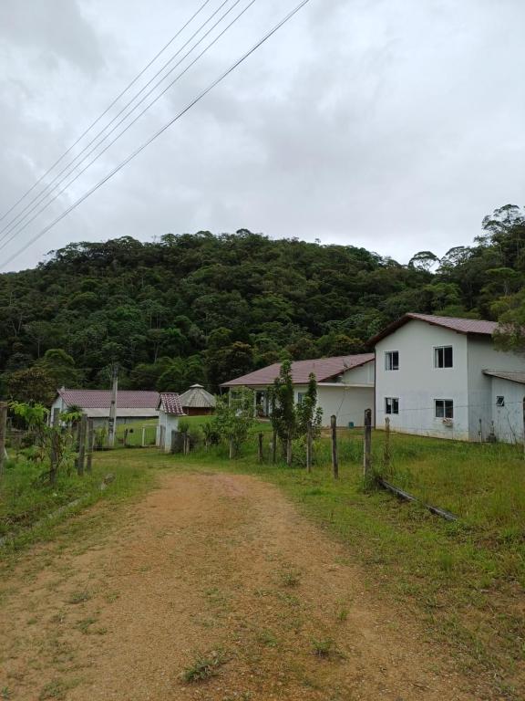 a dirt road in front of a white house at Sitio São Francisco de Assis in São Pedro de Alcântara