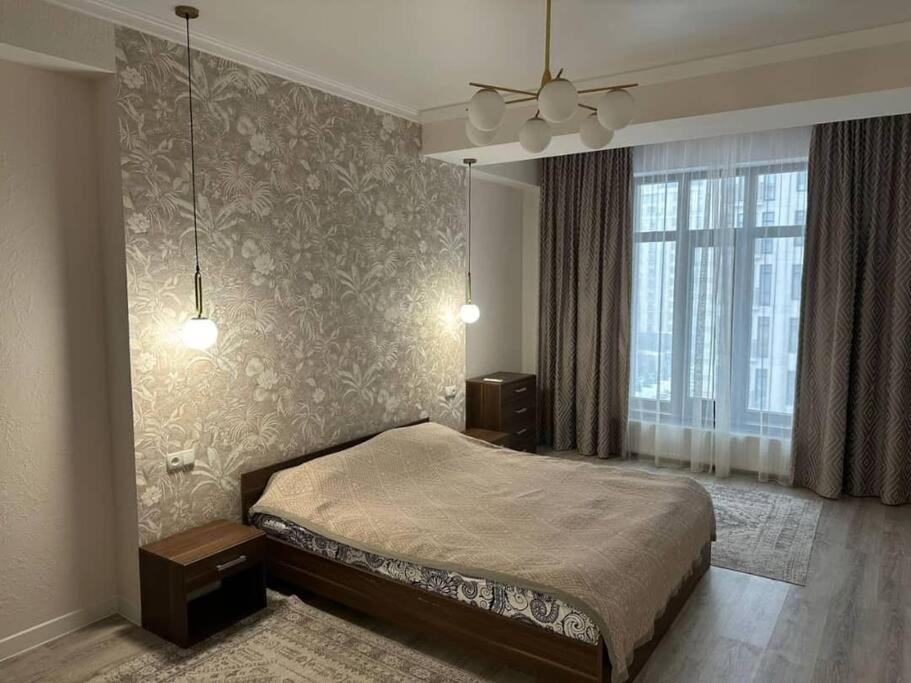 ein Schlafzimmer mit einem Bett und einem großen Fenster in der Unterkunft Апартамент in Bischkek