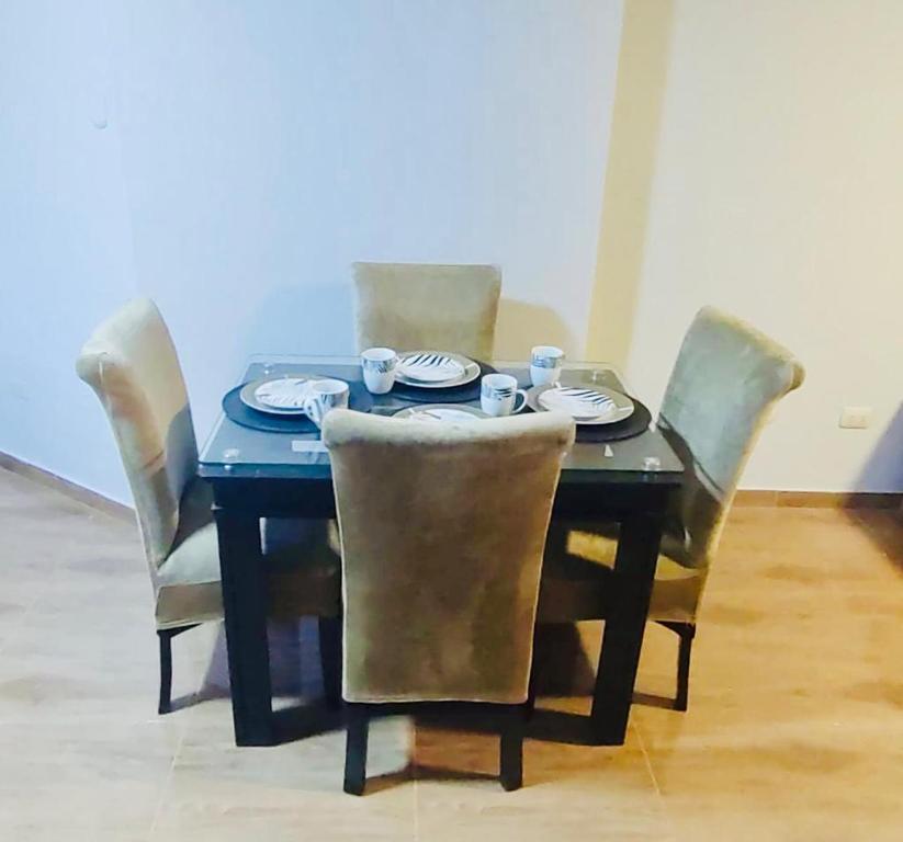 una mesa de comedor con sillas y una mesa con platos. en Diaz Ponce de León, en Tacna
