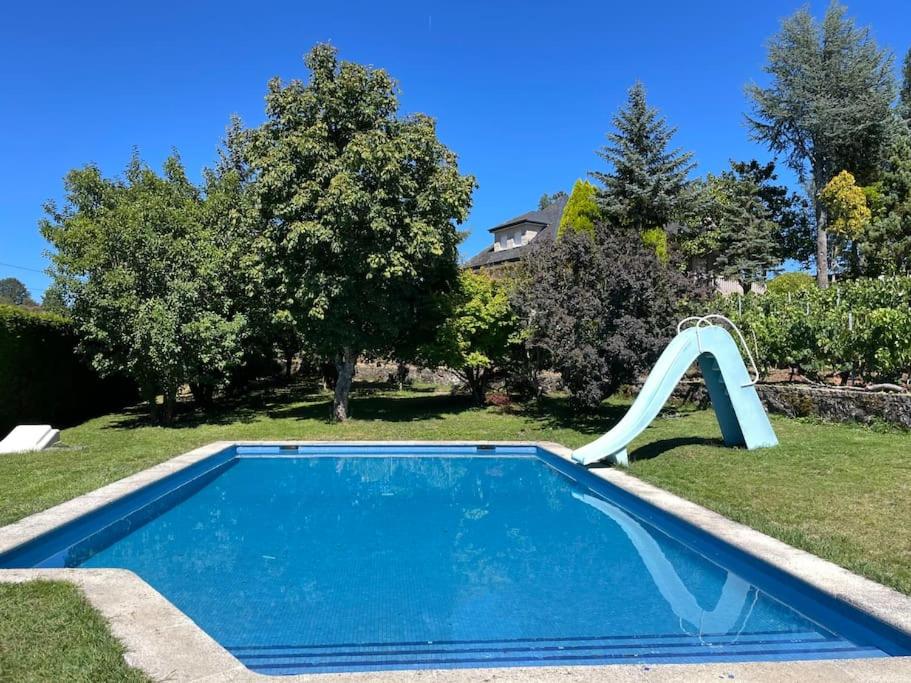 una piscina con un tobogán en un patio en Villa Airexe. Chalet con piscina y tenis en la Ribeira Sacra, en Taboada