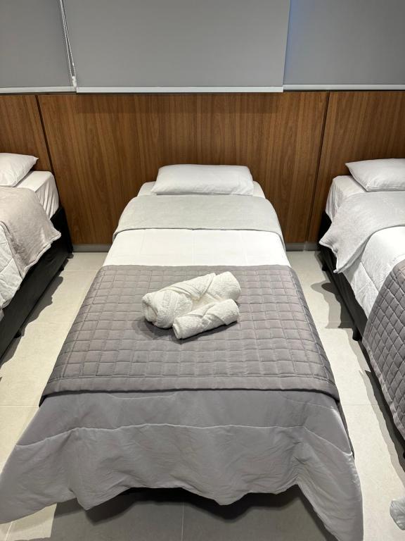 een paar bedden in een kamer met een handdoek bij Flat Canção Nova in Cachoeira Paulista