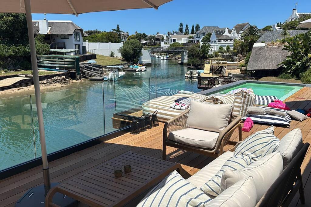 a deck with lounge chairs and a swimming pool at Laid back luxury canal house in St Francis Bay
