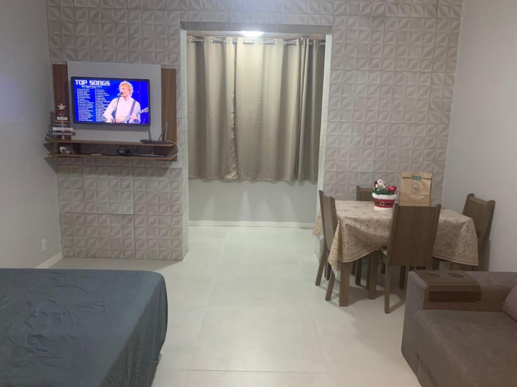uma sala de estar com uma televisão e uma mesa e cadeiras em Jk Beira Mar região central de Capão em Capão da Canoa