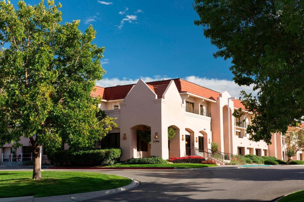 um grande edifício branco com uma árvore e uma rua em The Querque Hotel em Albuquerque