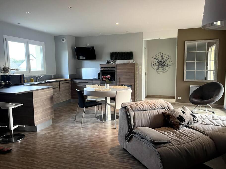 uma sala de estar com um sofá, uma mesa e uma cozinha em Accès direct plage 100m em Jullouville-les-Pins
