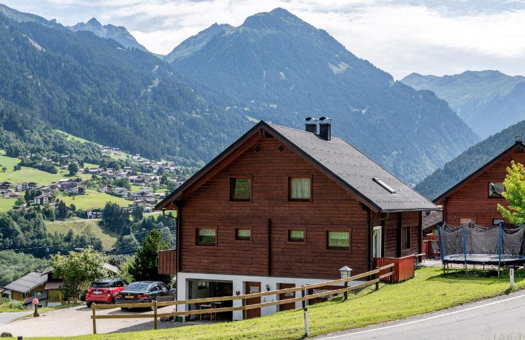 uma grande casa de madeira com montanhas ao fundo em Silvretta Nova em Sankt Gallenkirch