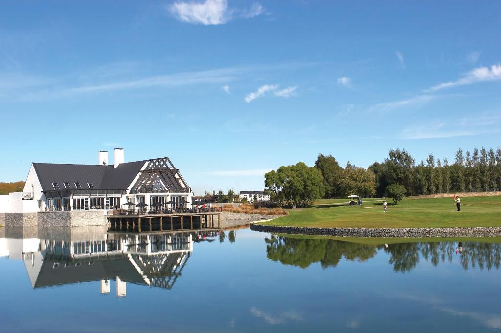 a house on a golf course next to a lake at Peppers Clearwater Resort in Christchurch