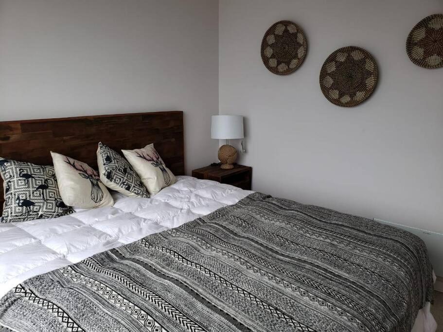 um quarto com uma cama com almofadas e relógios na parede em Dpto Vita3 2D2B Puerto Varas em Puerto Varas