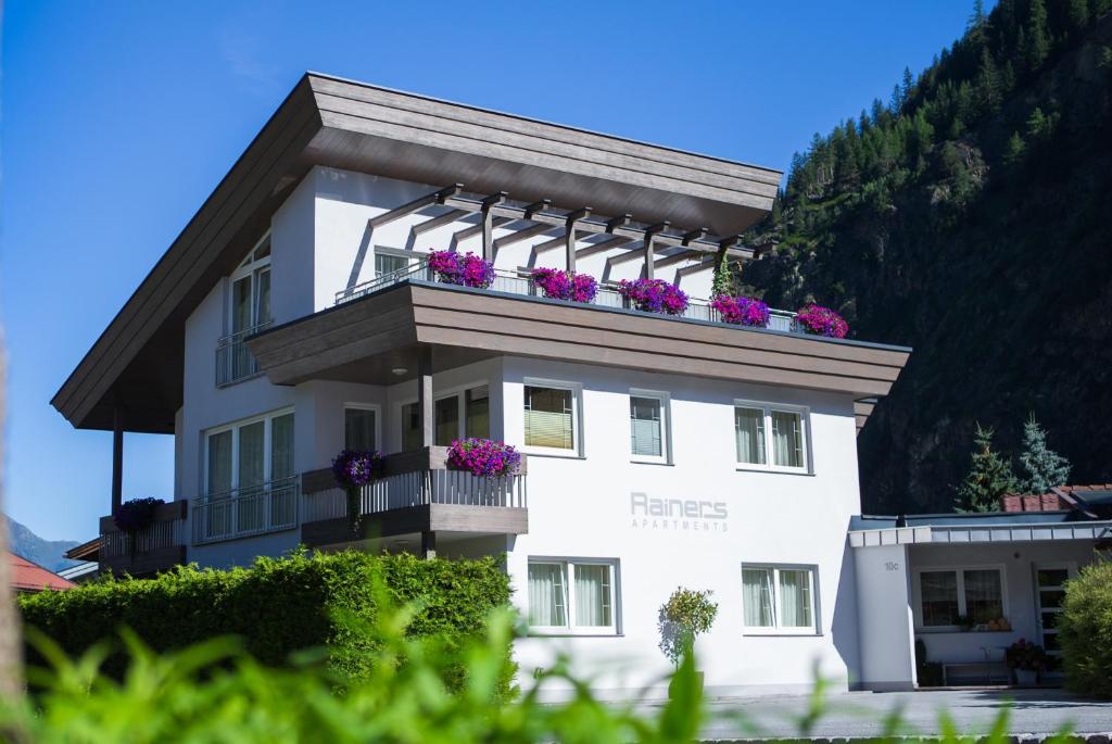ein weißes Gebäude mit Blumen auf dem Balkon in der Unterkunft Rainer's Appartements in Längenfeld
