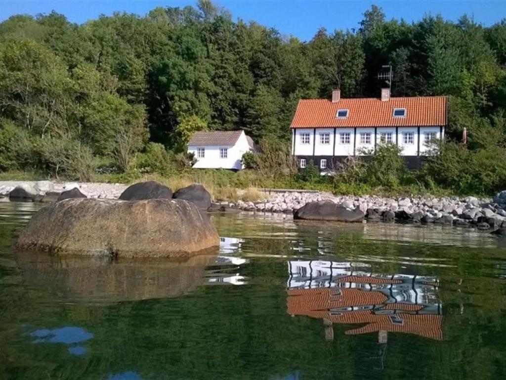 a house on the shore of a body of water at Holiday Home Asgot - 15m from the sea in Bornholm by Interhome in Hasle